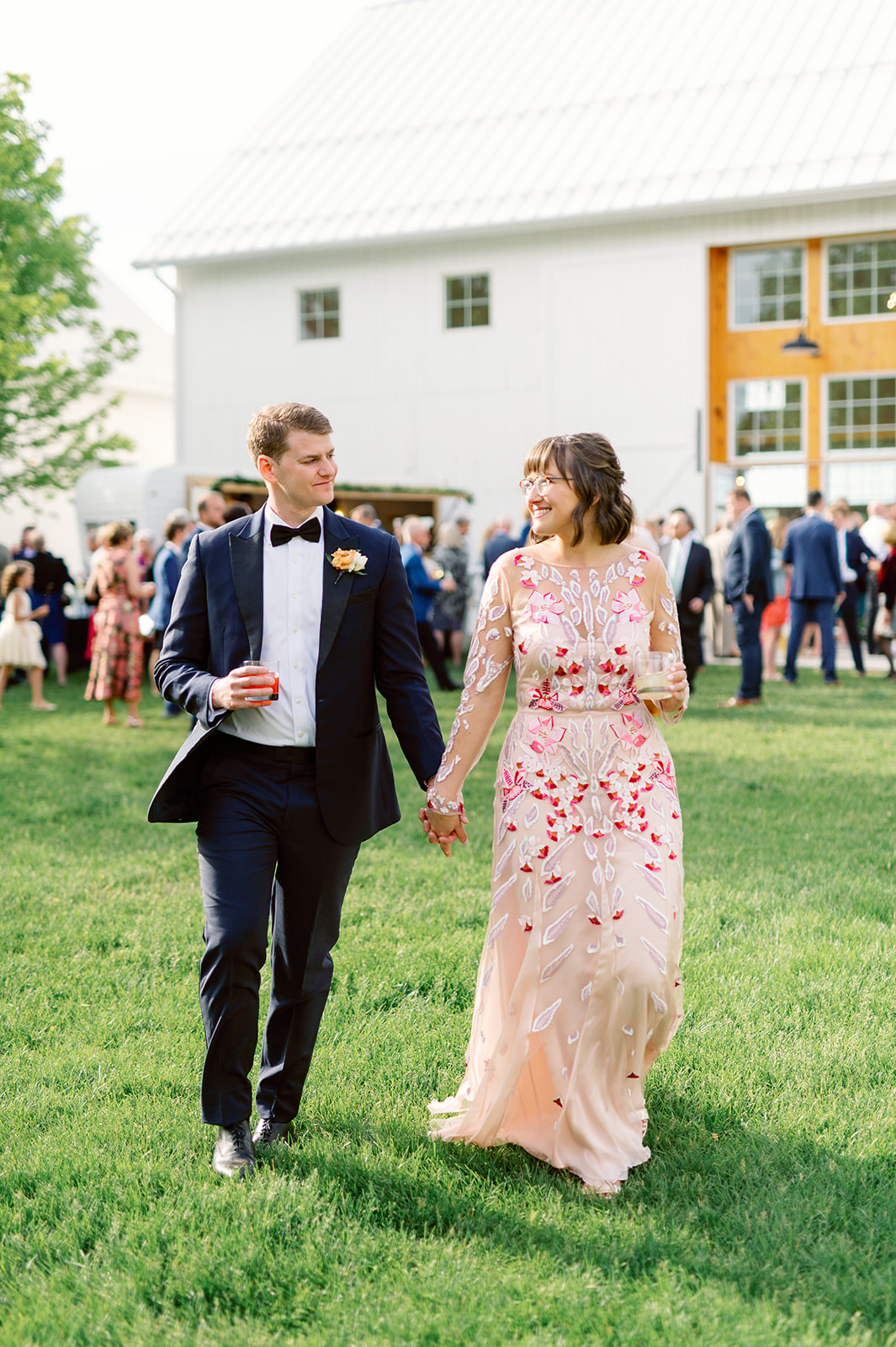 Newlyweds hold hands while walking away from their cocktail hour at a Unique Wedding Venues Minnesota