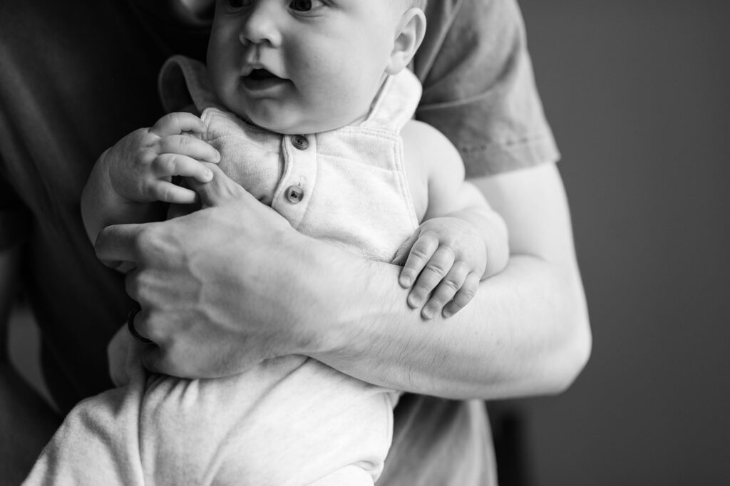 6 month old baby boy hands on dad's arm