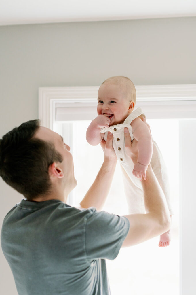 dad holding baby boy in the air, smiling