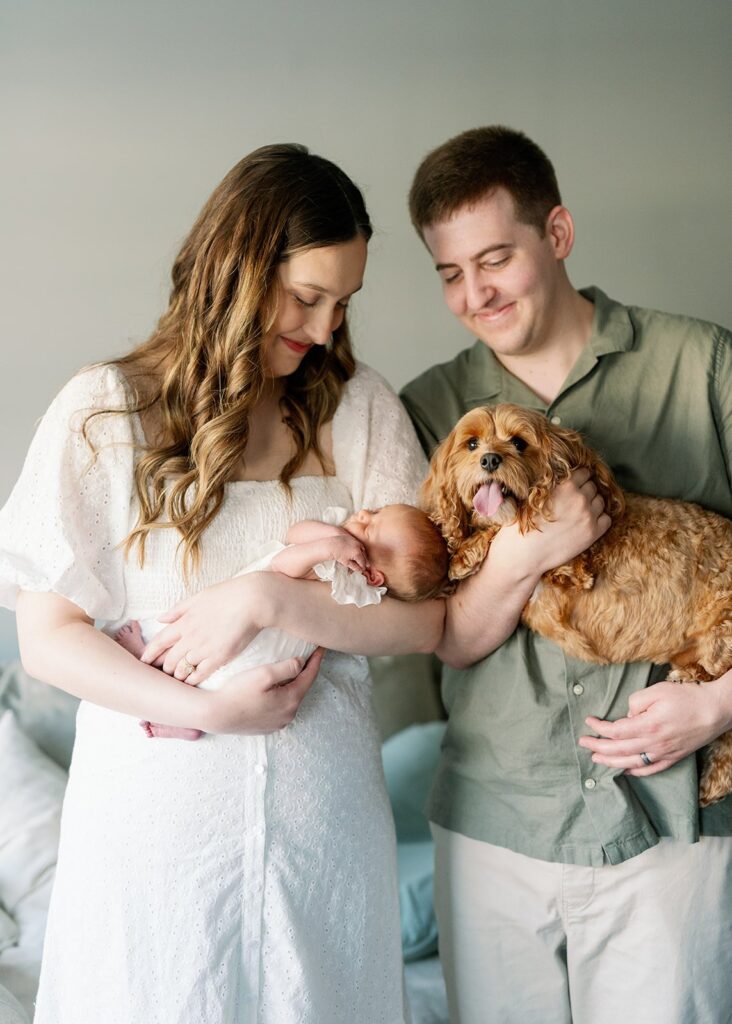 parents holding newborn baby and dog at their in home lifestyle newborn session in Minnesota
