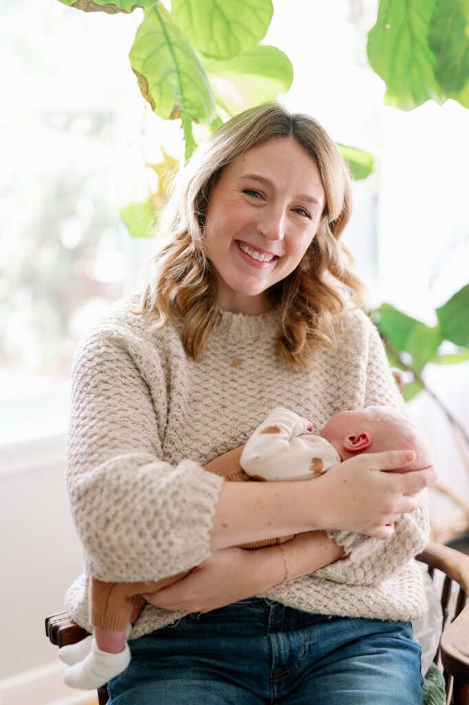 in home newborn photography of a mom holding newborn baby and smiling