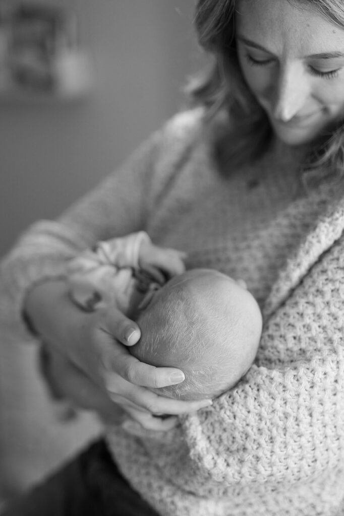 mom holding newborn baby at in home newborn lifestyle session in MN