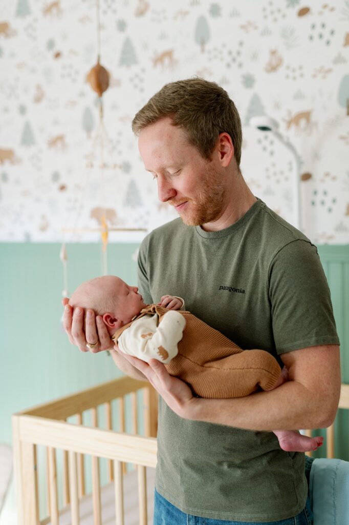 new dad holding and looking at newborn baby in the nursery, in Minnesota