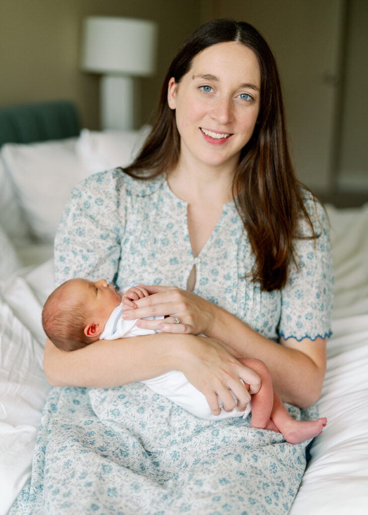 mom looking at camera holding newborn baby to show what to wear for newborn pictures