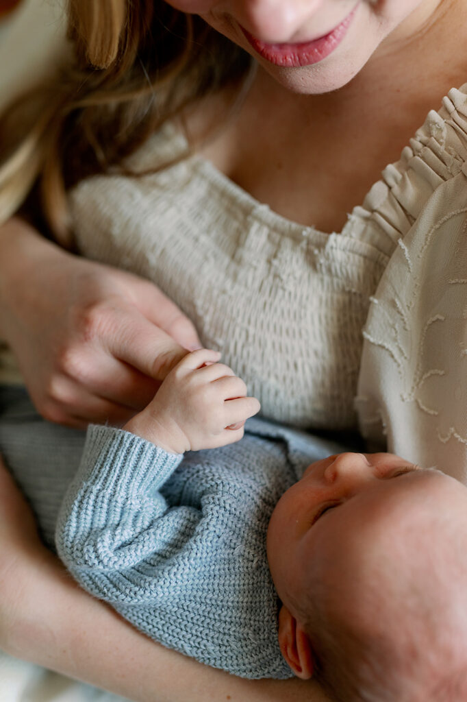Twin Cities Newborn Photography | Bauer Creative Closeup of mom snuggling newborn while the baby grips her finger at this Twin Cities Newborn Photography session by Bauer Creative.