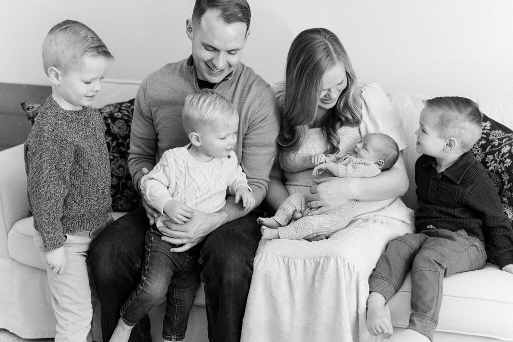 Twin Cities Newborn Photography | Bauer Creative Family sits on the couch holding their newborn baby during their Twin Cities newborn photography session.