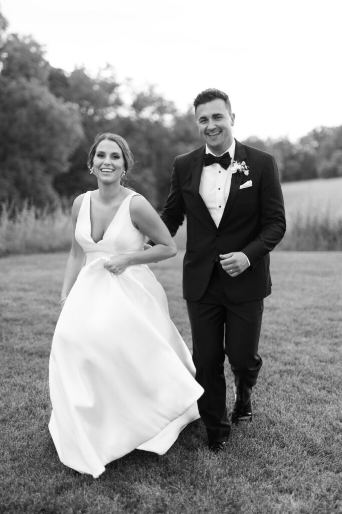 Best wedding photographers in MN capturing a joyful couple walking together and smiling during their wedding portraits. 