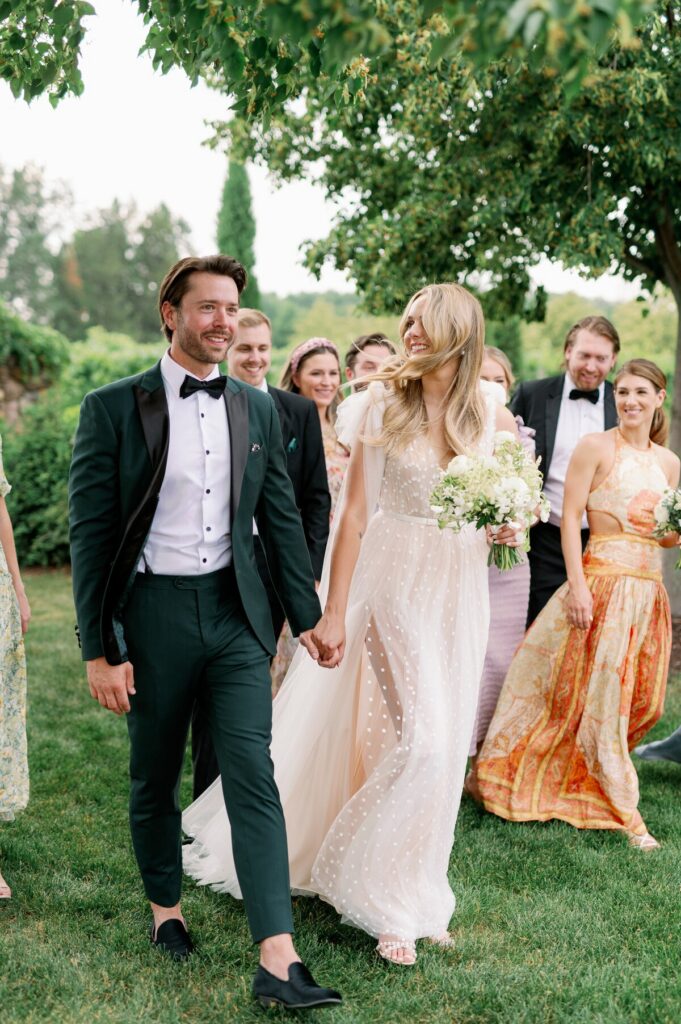 Wedding photographers in Minneapolis capturing a couple walking with their wedding party through a garden setting. 