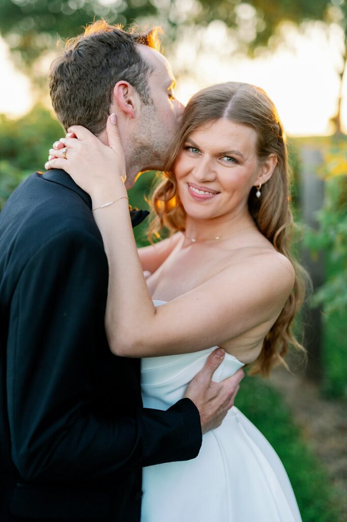 Wedding photographers in Minneapolis capturing a groom kissing the bride’s cheek during golden hour. 