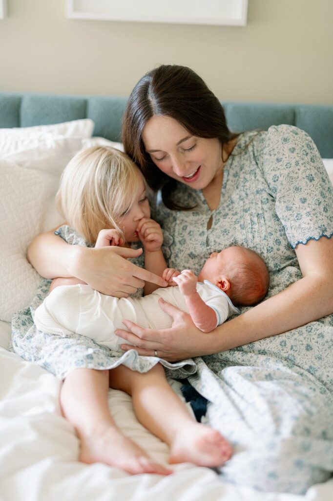 Mom and toddler posing with baby for newborn photography session in the Twin Cities.