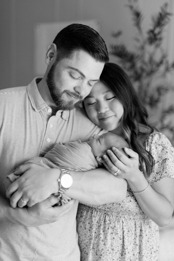Couple posing with their baby for newborn photography session in the Twin Cities, MN.